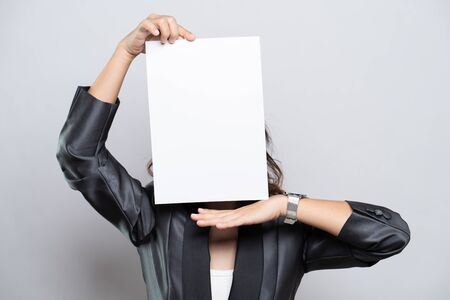 Business woman showing paper cover her face isolated over white backgroundの写真素材