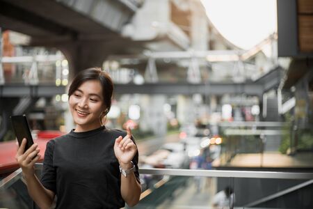 Happy asian woman looking at her phone in the cityの写真素材