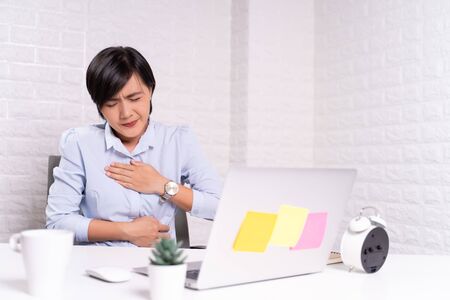 Woman has stomachache at officeの写真素材