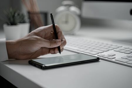 Close up shot of businessman working in office holding smart phone with blank screenの写真素材