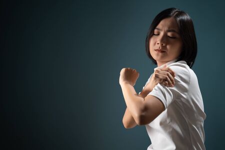 Asian woman was sick with body pain office syndrome and standing isolated over blue background. Health care concepts.の写真素材