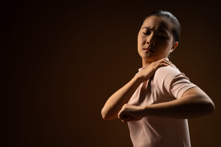 Asian woman was sick with body pain touching her body and standing isolated on beige background. Low...