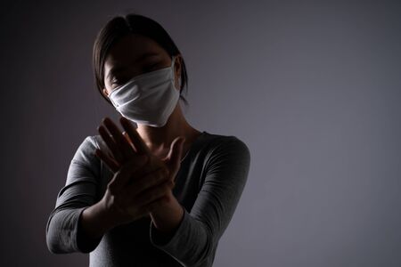 Asian woman was sick with body pain touching her body and standing isolated on background. Low key.の写真素材
