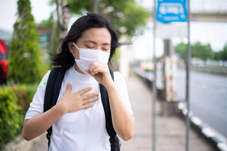 Asian woman wearing protective face mask prevention virus and pollution, coughing and standing at department store. New lifestyle with Corona Virus COVID-19.の写真素材