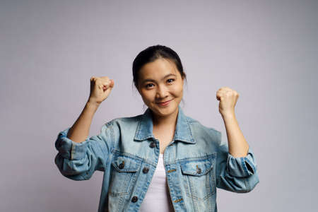 Asian woman happy confident standing showing her fist make a winning gesture isolated on white background.の写真素材