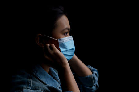 Asian woman wearing protective mask isolated on background. Low key.の写真素材