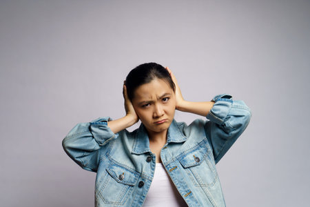 Asian woman bored and annoyed, covering her ears isolated on white background.の写真素材