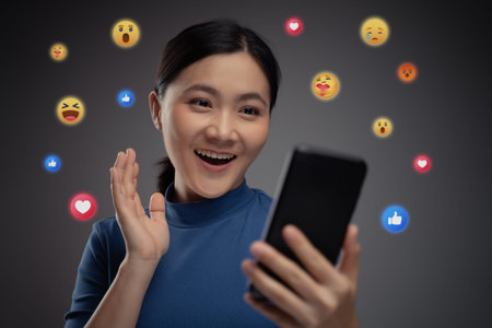 Asian woman using smart phone for social media with emoticon bubble. Isolated on background.