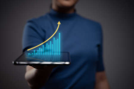 Woman using tablet planning digital marketing with chart hologram effect.の写真素材