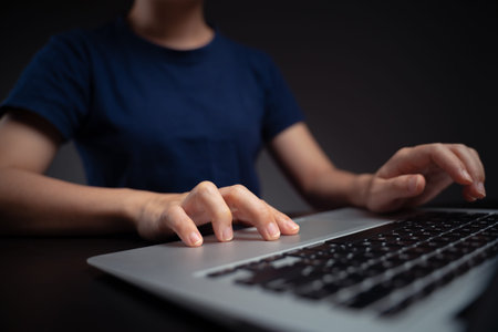 Asian woman working on laptop scans face by smart phone using facial recognition system.