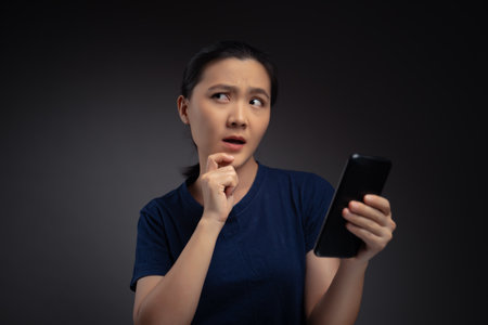 Asian woman working on laptop scans face by smart phone using facial recognition system.の写真素材