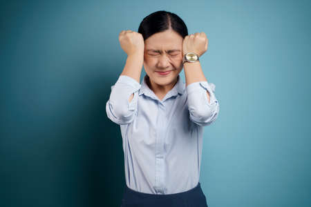 Asian woman was sick with fever isolated on blue background.の写真素材