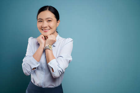 Asian woman happy surprised standing with copy space isolated on blue background.の写真素材