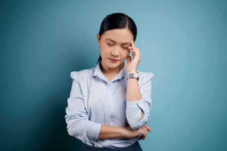 Asian woman happy confident standing showing her fist make a winning gesture isolated on blue background.の写真素材