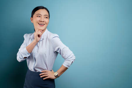 Asian woman happy surprised standing with copy space isolated on blue background.の写真素材