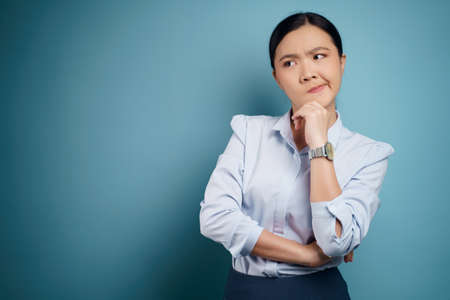 Asian woman happy confident standing showing her fist make a winning gesture isolated on blue background.の写真素材