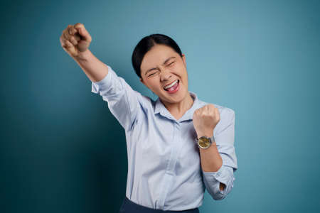 Asian woman happy surprised standing with copy space isolated on blue background.の写真素材
