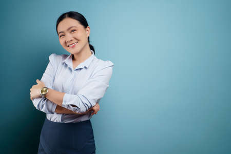 Asian woman happy confident standing showing her fist make a winning gesture isolated on blue background.の写真素材