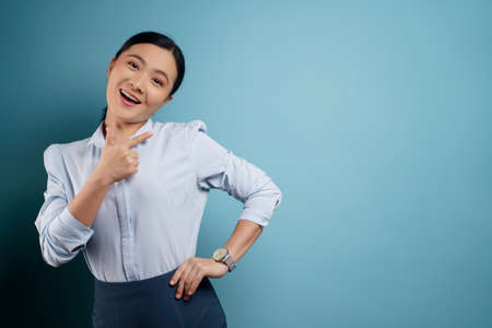Asian woman happy surprised standing with copy space isolated on blue background.の写真素材