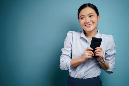 Asian woman happy surprised standing with copy space isolated on blue background.の写真素材