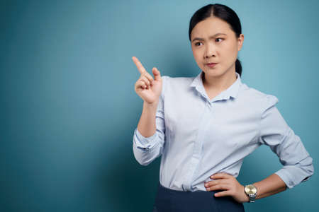 Asian woman happy surprised standing with copy space isolated on blue background.の写真素材