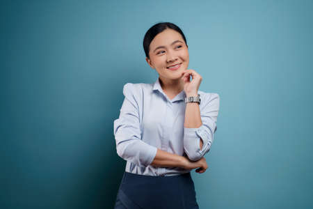 Asian woman happy surprised standing with copy space isolated on blue background.の写真素材