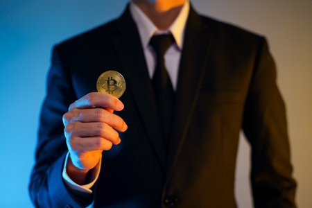 Close up shot of Businessman in black suit holding golden coin isolated on background.の写真素材