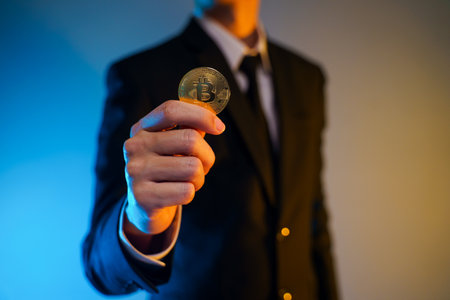 Close up shot of Businessman in black suit holding golden coin isolated on background.の写真素材