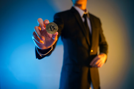 Close up shot of Businessman in black suit holding golden coin isolated on background.の写真素材