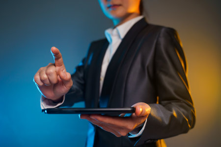 Close up shot of business woman holding smart phone in black suit. Elegant smart on black background.の写真素材