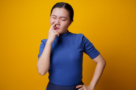 Asian woman with headphones listening to music from smart phone isolated on yellow background.の写真素材