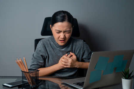 Asian woman happy smiling looking at copy space, working on a laptop at office. isolated on gray background.の写真素材