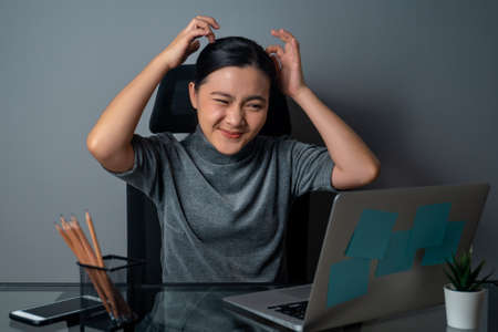 Asian woman working on a laptop was sick with stomach ache sitting at office. isolated on gray background.の写真素材