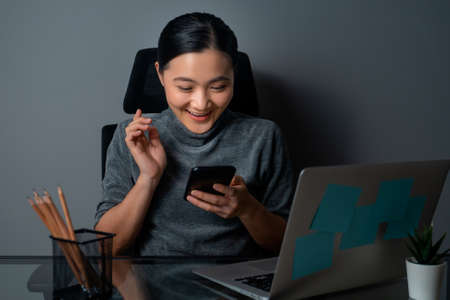 Asian woman happy smiling looking at copy space, working on a laptop at office. isolated on gray background.の写真素材