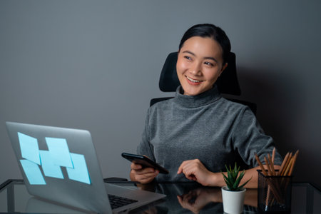 Asian woman happy smiling looking at copy space, working on a laptop at office. isolated on gray background.の写真素材