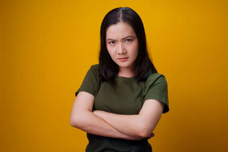 Asian woman standing and angry isolated over yellow background.の写真素材