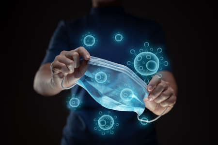 Close up shot of hands holding protective face mask with virus vector hologram effect.の写真素材