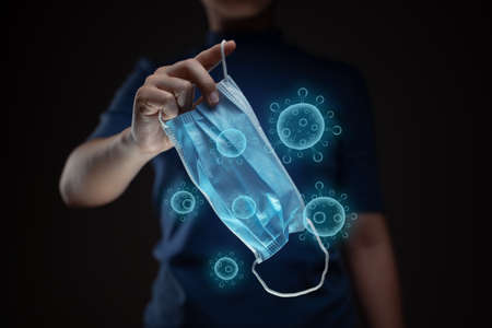 Close up shot of hands holding protective face mask with virus vector hologram effect.の写真素材