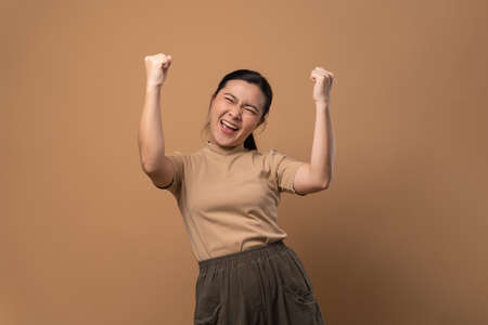 Happy woman with headphones and listening to music isolated on beige background.の写真素材