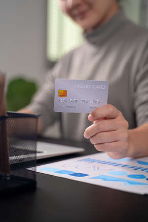 Close up shot of females  hands holding credit card typing message on laptop for shopping online at home office.の写真素材