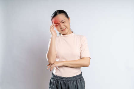 Asian woman was sick with headache touching her head with red spot and standing isolated on white background.の写真素材