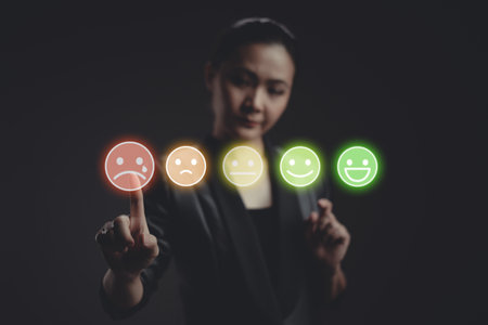 Asian woman voting and pressing angry face emoticon on virtual touch screen, isolated on background. Customer service satisfaction survey concept.の写真素材