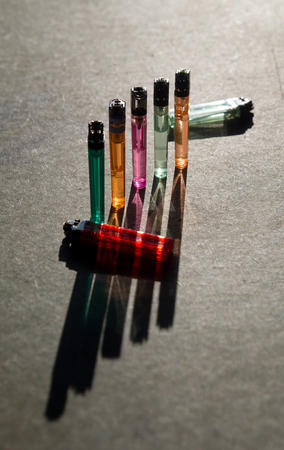 Six colorful gas lighters in the sunshineの写真素材