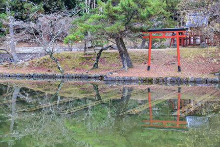 The red torii gate by the lake and its reflection in the water