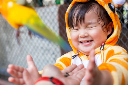 A trip in the zoo, A cute child girl feeding the Parrot in the large cage. The parrot came to eat the sunflower seeds in hand.の写真素材