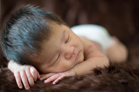 Cute Asian newborn baby on brown fur blanket background.
Nice portrait of little child boy.の写真素材