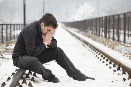 Sad man in railroad trackの写真素材