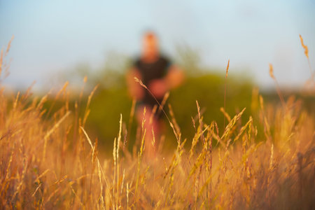 Young man is running on summer meadow - selective focus on grassの写真素材