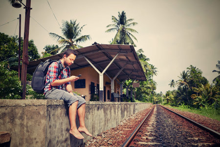 Young traveler with mobil phone in the railwayの写真素材