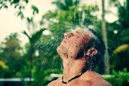 Muscular man is having shower in the rain.の写真素材